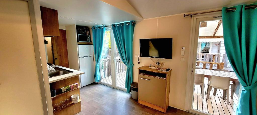 une cuisine avec des rideaux bleus et une grande porte coulissante en verre dans l'établissement Camping Aux Portes De Cassis, à La Bédoule