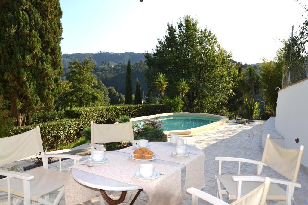 - une table et des chaises à côté de la piscine dans l'établissement Villa Costa Medea, à Camaiore