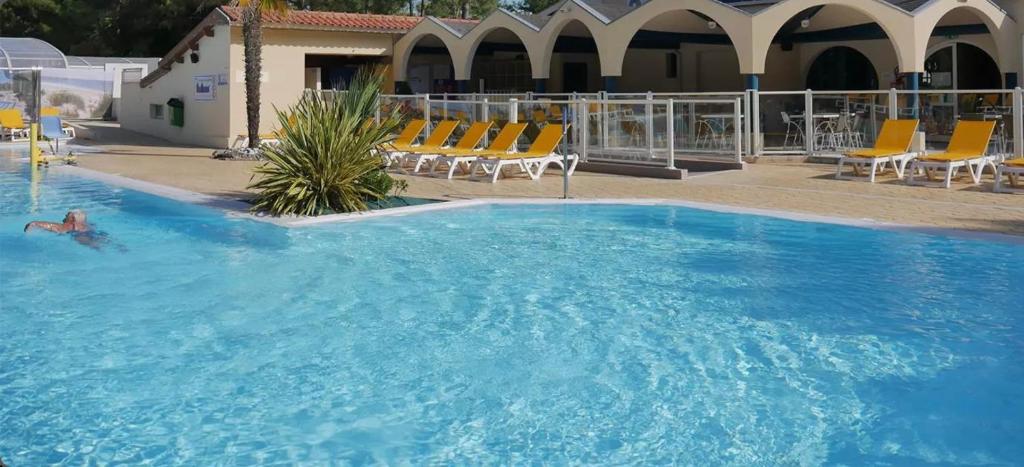 une grande piscine bleue avec des chaises dans un bâtiment dans l'établissement Mobilhome 6-8 personnes Clim, à Saint-Jean-de-Monts