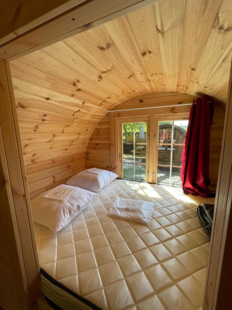 - une chambre avec un grand lit dans une maison en bois dans l'établissement TONNEAU HERBERGEMENT INSOLITE AU CAMPING DES NIERES, à Ébreuil