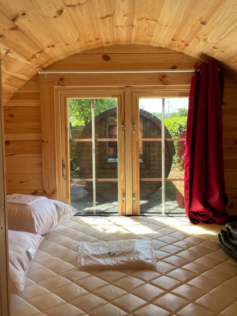 - une chambre avec un lit et une grande porte en verre dans l'établissement TONNEAU HERBERGEMENT INSOLITE AU CAMPING DES NIERES, à Ébreuil