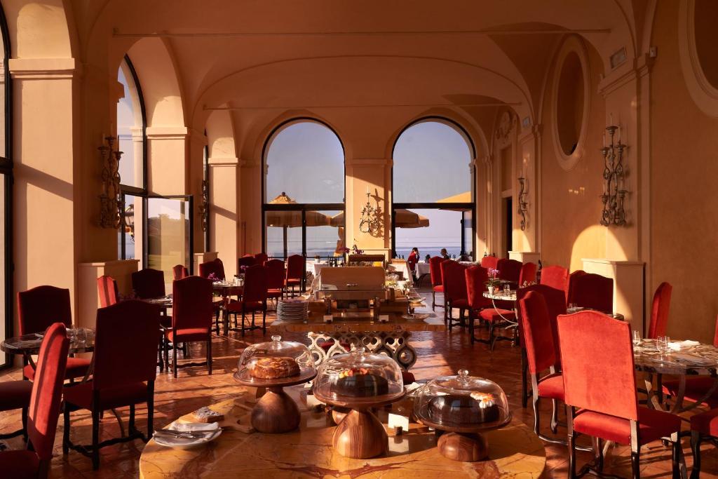 une salle à manger avec des tables et des chaises et l'océan dans l'établissement La Posta Vecchia Hotel, à Ladispoli
