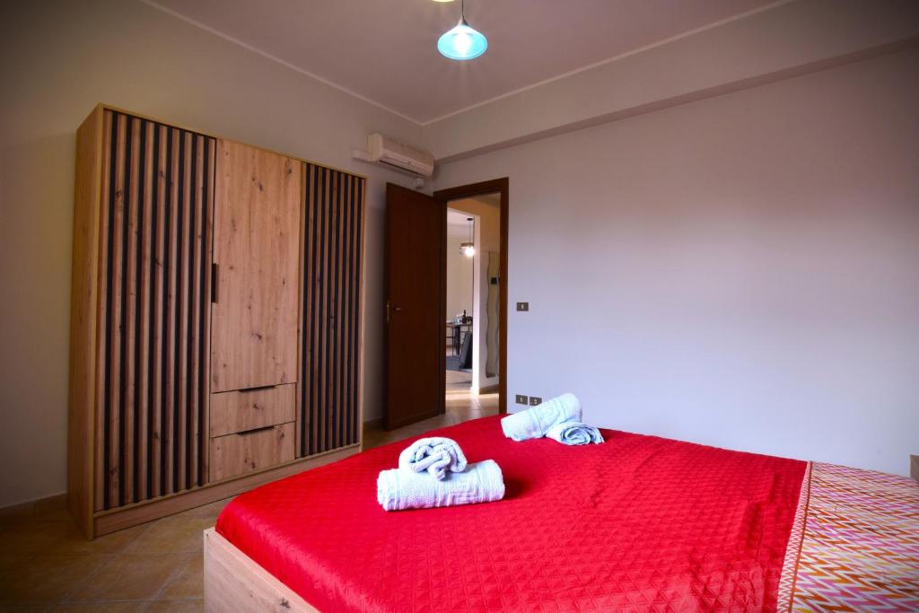 une chambre avec un lit rouge avec des serviettes dessus dans l'établissement Villa CLARA, à Altavilla Milicia