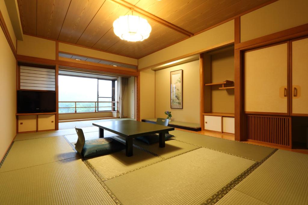 un salon avec une table et une grande fenêtre dans l'établissement Tateyama Prince Hotel, à Omachi
