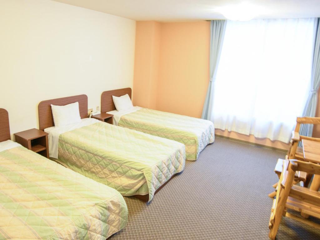 une chambre d'hôtel avec trois lits et une fenêtre dans l'établissement Ryokan HANAEMI, à Otaru