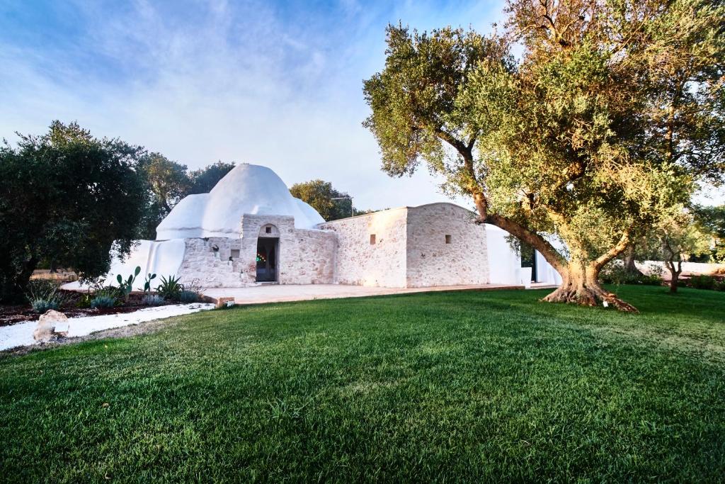un bâtiment avec un dôme et un arbre dans l'herbe dans l'établissement Alma Apulia " Italian Dolce Vita", à Ostuni