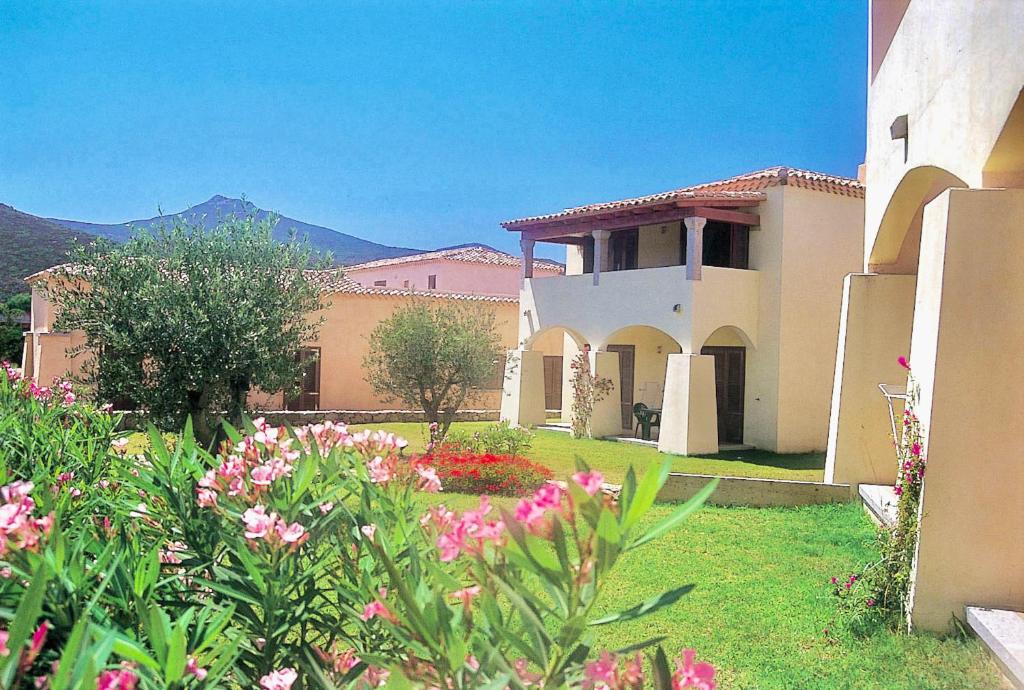 une maison avec un jardin avec des fleurs dans la cour dans l'établissement ISA-Residence with private beach in Marinella, à Marinella