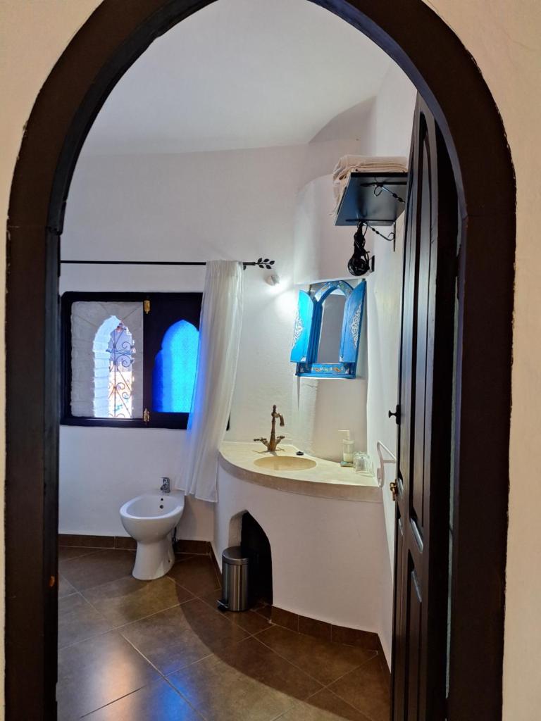 une arche menant à une salle de bains avec lavabo et toilettes. dans l'établissement Dar Gabriel, à Chefchaouen