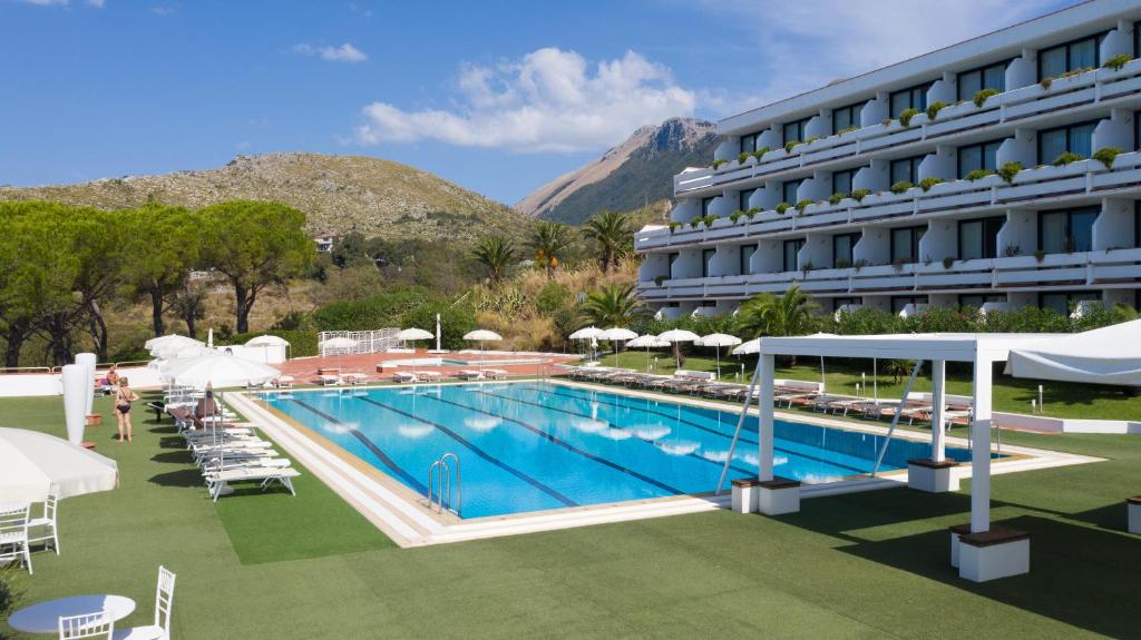 un hôtel avec une piscine dotée de chaises et de parasols dans l'établissement Grand Hotel Pianeta Maratea Resort, à Maratea