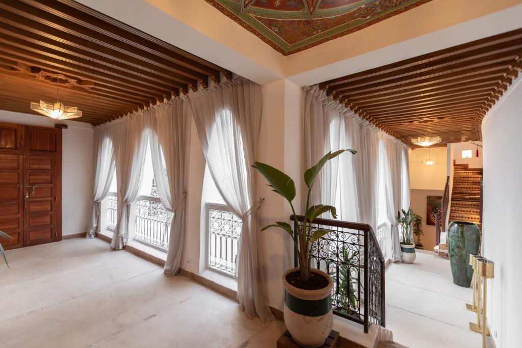 Cette chambre dispose de grandes fenêtres et d'une plante en pot. dans l'établissement Riad N'S & Spa, à Marrakech