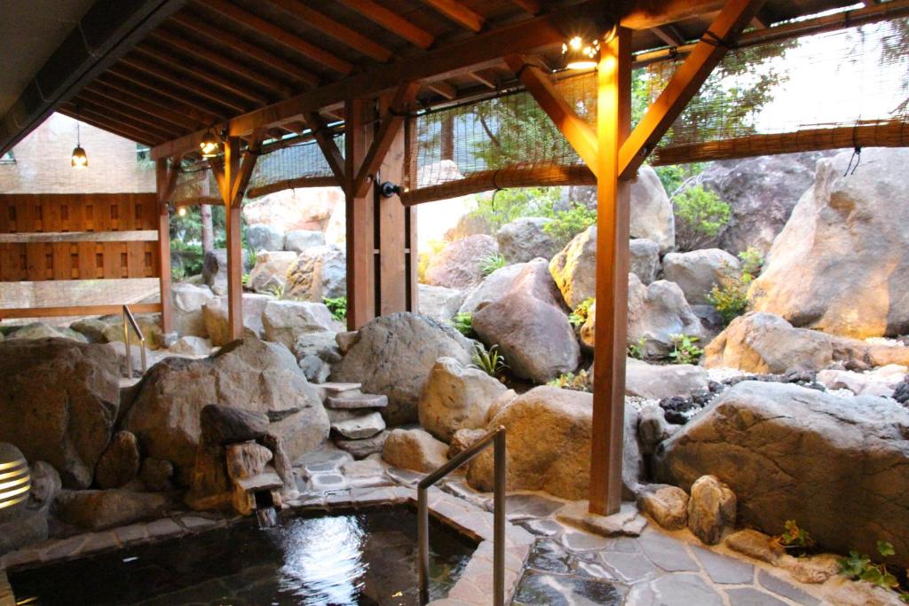 une chambre avec des rochers et un étang dans un bâtiment dans l'établissement Maruyama Onsen Kojyokan, à Minami Uonuma