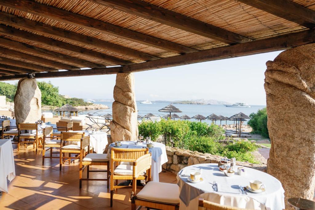 un restaurant avec des tables et des chaises et une vue sur l'océan dans l'établissement Hotel Pitrizza, Costa Smeralda, à Porto Cervo