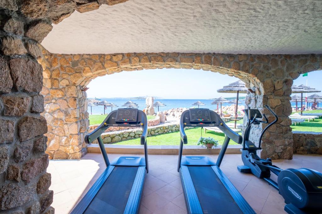une salle de sport avec 3 tapis de course dans un mur en pierre dans l'établissement Hotel Pitrizza, Costa Smeralda, à Porto Cervo