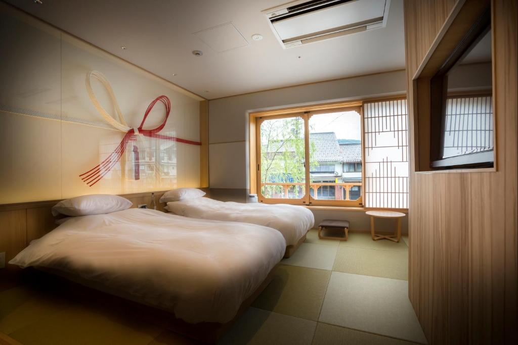 - 3 lits dans une chambre avec un papillon sur le mur dans l'établissement Kinosaki onsen Tokitotoki, à Kinosaki