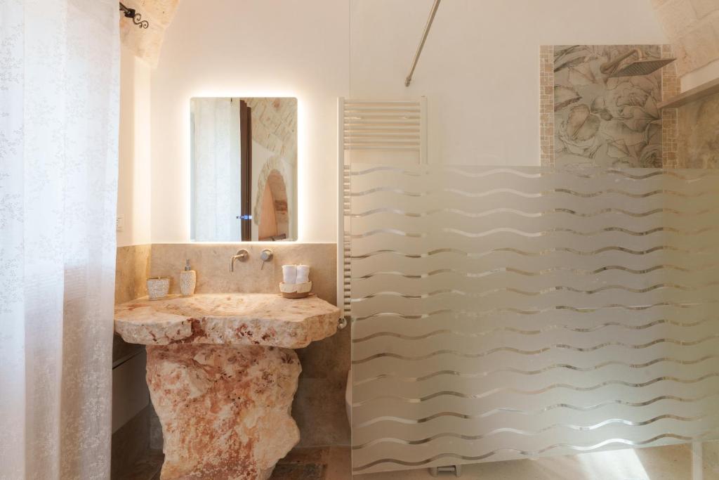 une salle de bain avec un lavabo et une douche dans l'établissement Trulli Petrantiqua con piscina, à Locorotondo 36 autres photos