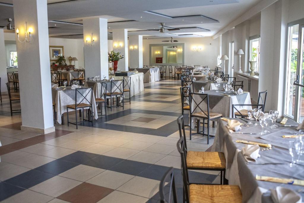 une salle à manger avec des tables et des chaises blanches dans l'établissement Hotel Enterprise, à Montalto di Castro