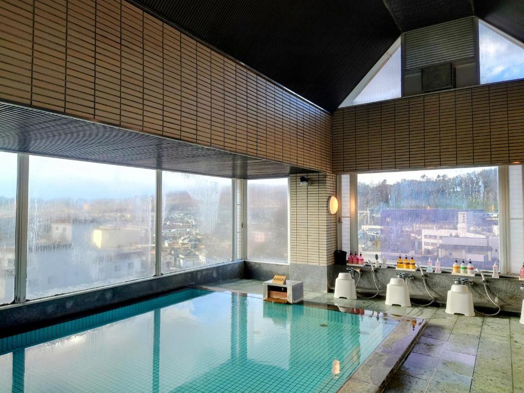 une piscine dans un immeuble avec de grandes fenêtres dans l'établissement Itoen Hotel Asamanoyu, à Matsumoto