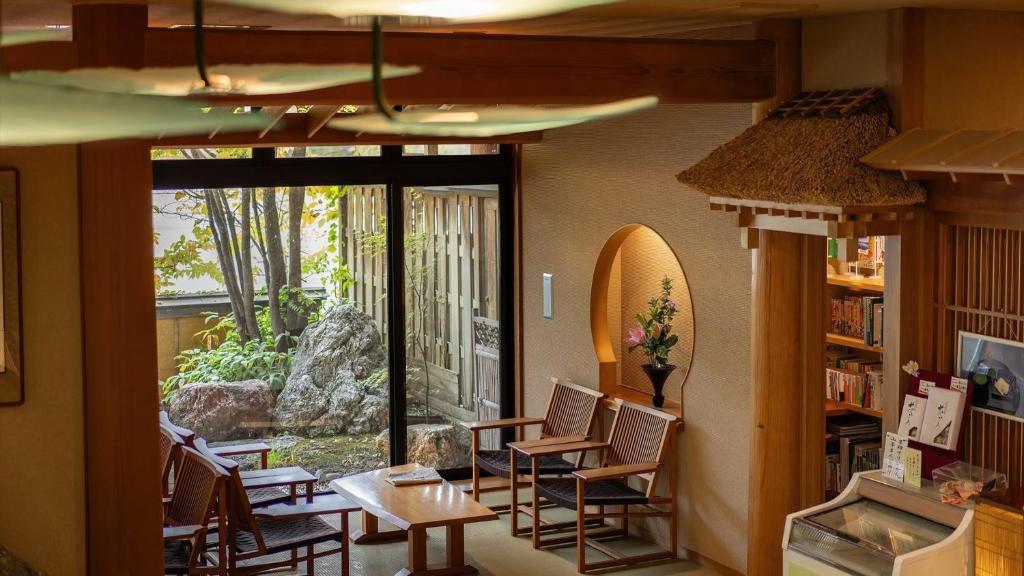 une chambre avec des chaises, des tables et une grande fenêtre dans l'établissement Kashintei Shirahama, à Senboku