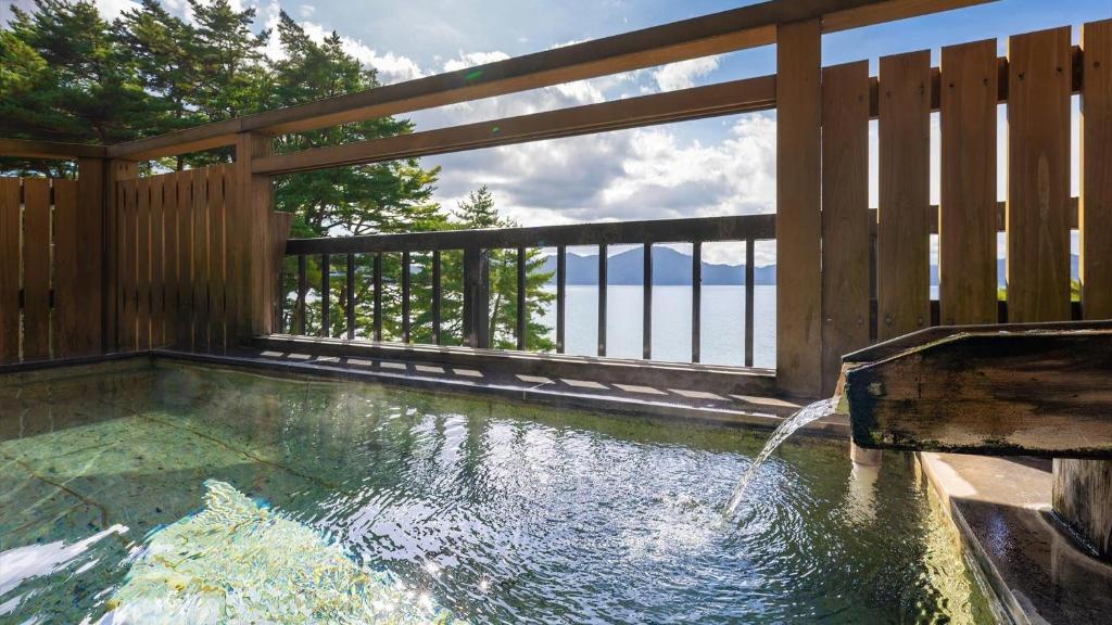 une piscine avec une clôture en bois et une fontaine dans l'établissement Katakurinohana, à Senboku