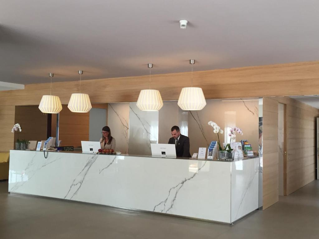deux personnes assises à un bureau de réception avec des ordinateurs portables dans l'établissement Hotel Fonzari, à Grado 43 autres photos