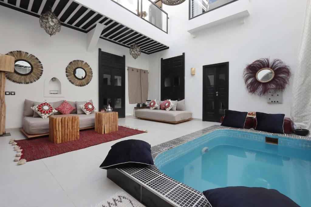 - un salon avec une piscine, un canapé et une table dans l'établissement Riad Modern Bed & Breakfast, à Marrakech