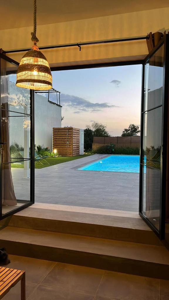 une porte-fenêtre ouverte avec vue sur une piscine dans l'établissement Villa Calimma, à Pachino