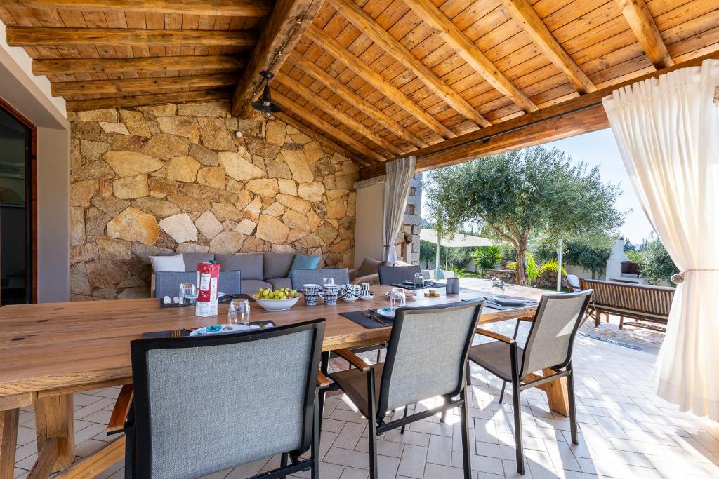 une salle à manger extérieure avec une table et des chaises en bois dans l'établissement DOMUS VILLA LORY Castiadas Cala Sinzias beach with swimming pool, à Castiadas