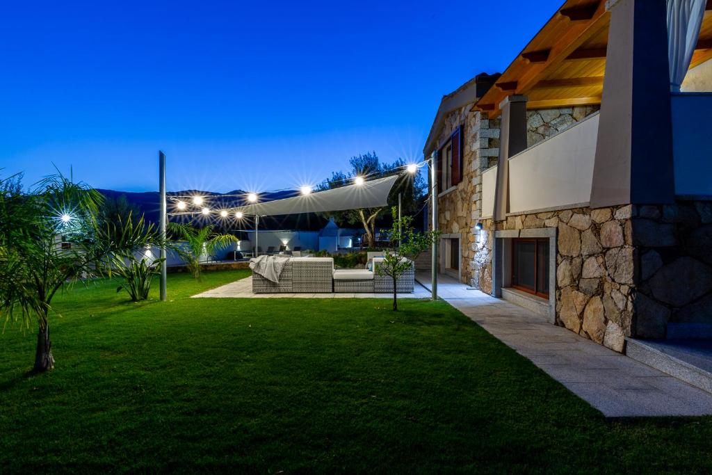 un patio avec un canapé dans une cour la nuit dans l'établissement DOMUS VILLA LORY Castiadas Cala Sinzias beach with swimming pool, à Castiadas