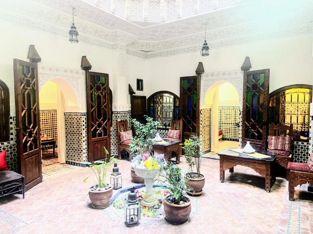 Cette grande chambre comprend des tables et des plantes en pot. dans l'établissement Riad Essaoussan, à Marrakech