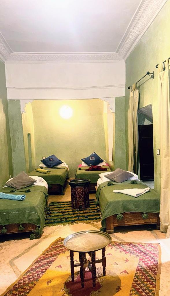 une chambre avec trois lits et une table dedans dans l'établissement Riad Essaoussan, à Marrakech