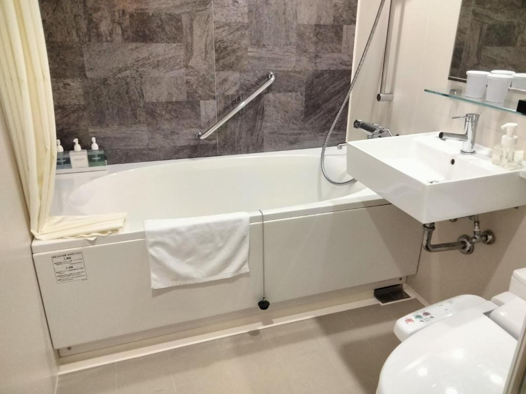 une salle de bain avec un lavabo, une baignoire et des toilettes dans l'établissement Resorpia Beppu, à Beppu
