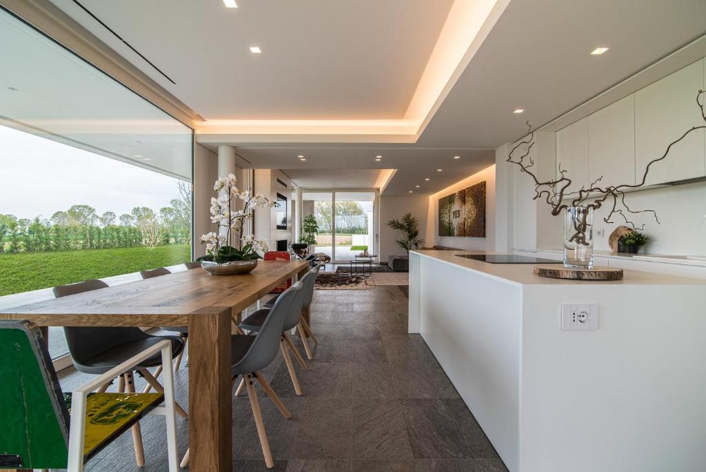 une cuisine ouverte et une salle à manger avec une table et des chaises en bois dans l'établissement STIMAHome villa con piscina privata, à Veggiano
