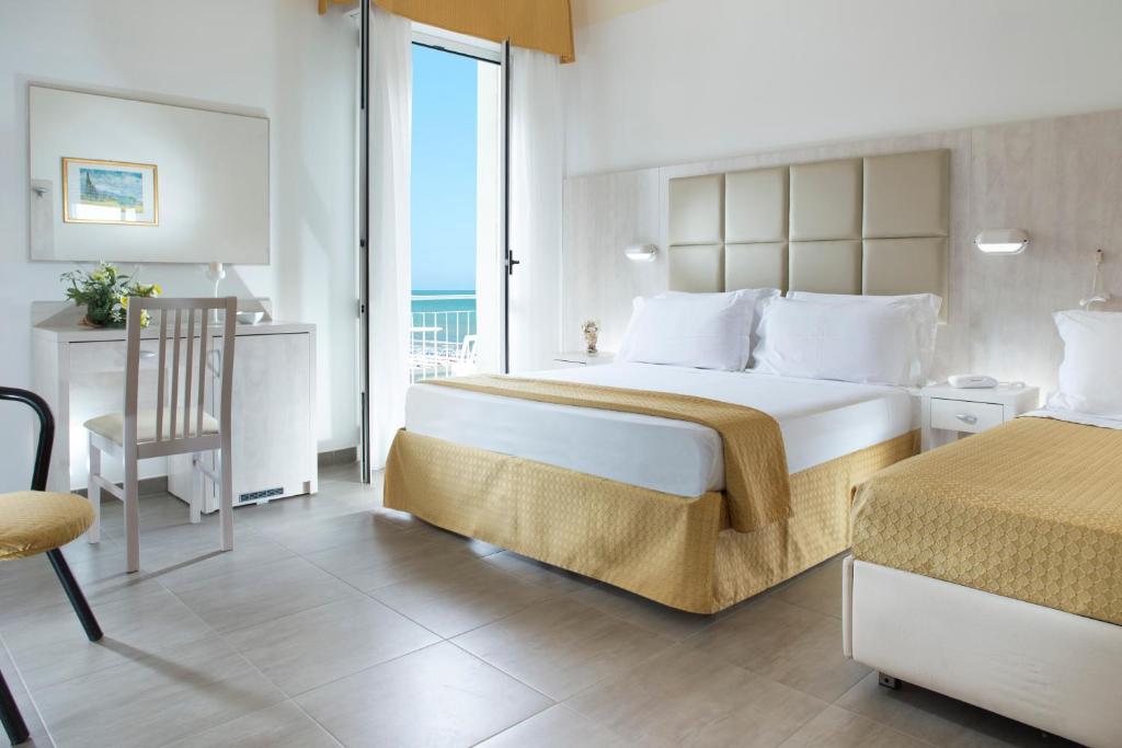 une chambre d'hôtel avec un grand lit et un balcon dans l'établissement Hotel Vela d'Oro, à Rimini