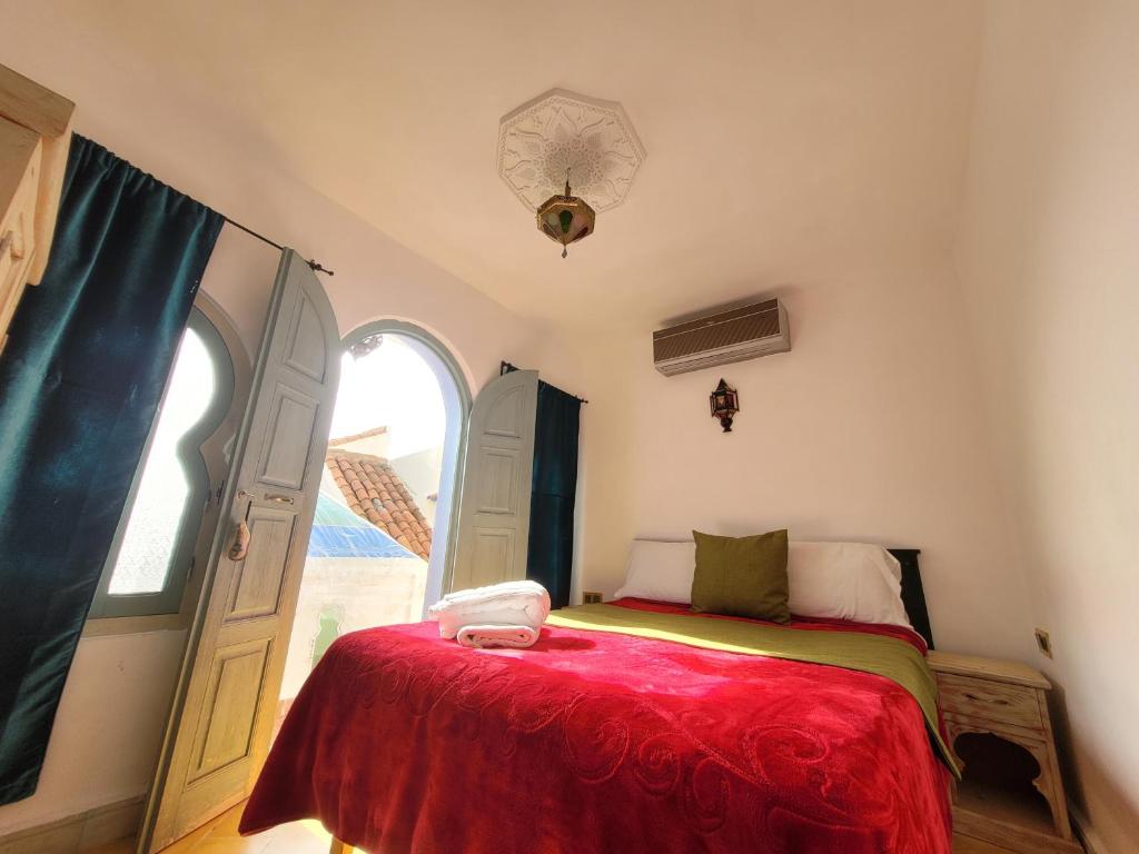 une chambre avec un lit avec une couverture rouge et une fenêtre dans l'établissement Honey Suckle, à Chefchaouen 37 autres photos