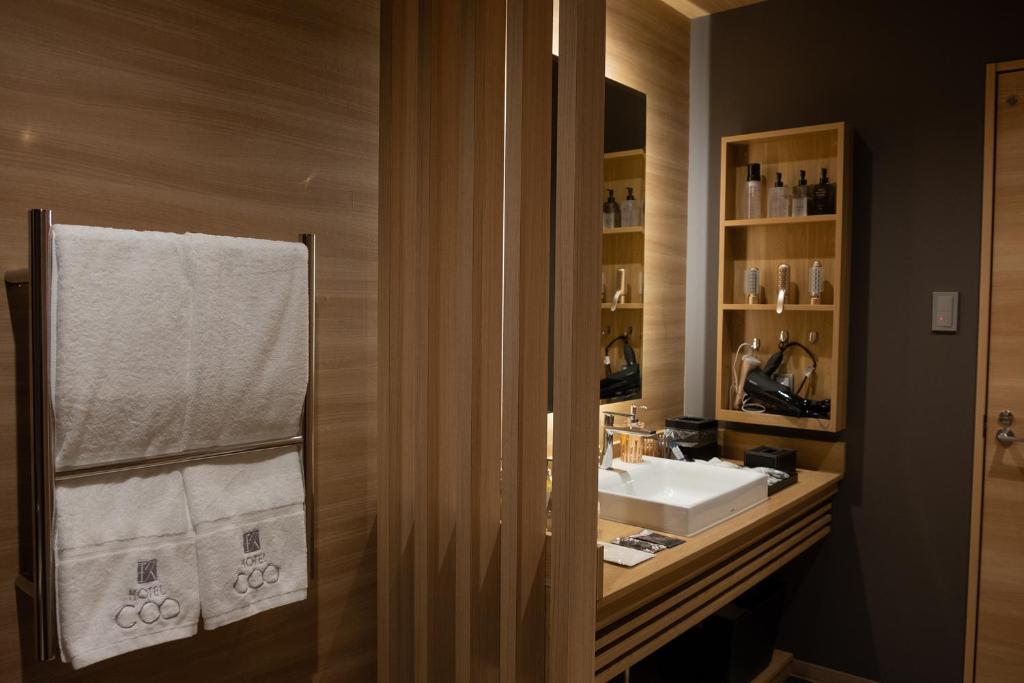 une salle de bain avec un lavabo et un miroir dans l'établissement ホテルCOO玖　男塾ホテルグループ, à Okayama
