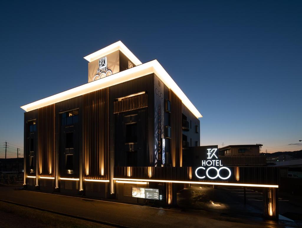 un bâtiment avec une enseigne au sommet dans l'établissement ホテルCOO玖　男塾ホテルグループ, à Okayama