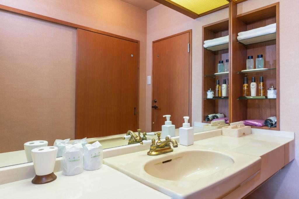 une salle de bain avec un lavabo et un miroir dans l'établissement Atagawakan, à Higashiizu