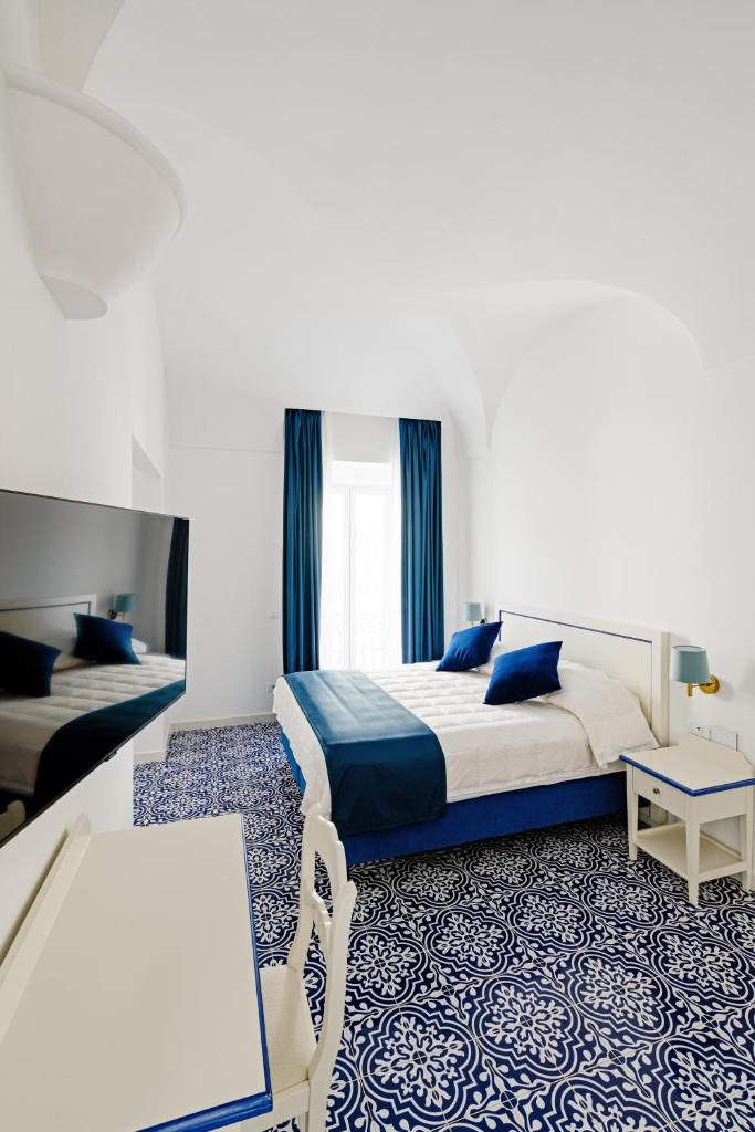 une chambre d'hôtel avec un lit, un bureau et une table dans l'établissement Hotel Da Raffaele, à Ischia