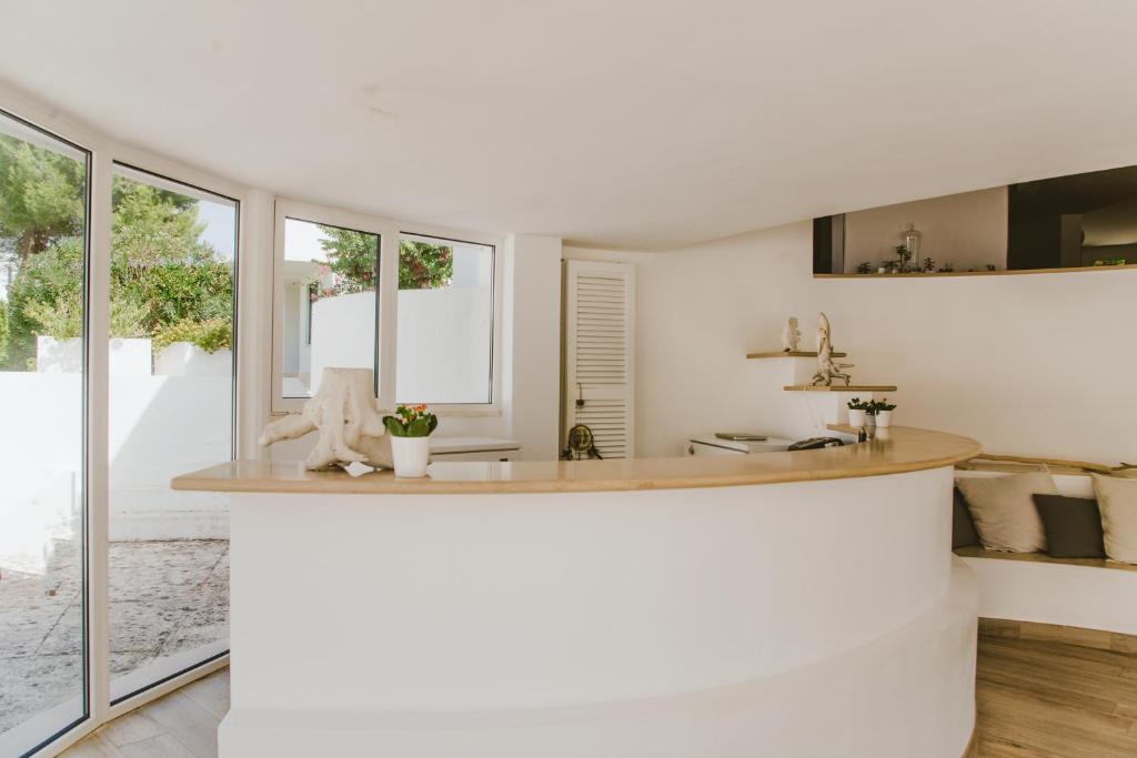 Il comprend une cuisine avec des murs blancs et de grandes fenêtres. dans l'établissement Residence Altair - Serra degli Alimini, à Otrante