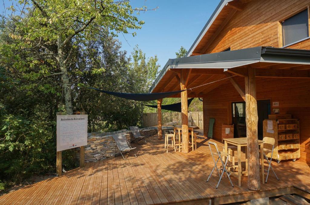 une terrasse en bois avec une tente, des tables et des chaises dans l'établissement Bivouac nature, Tentes Lodges dans les Cévennes, à Saint-Jean-du-Gard