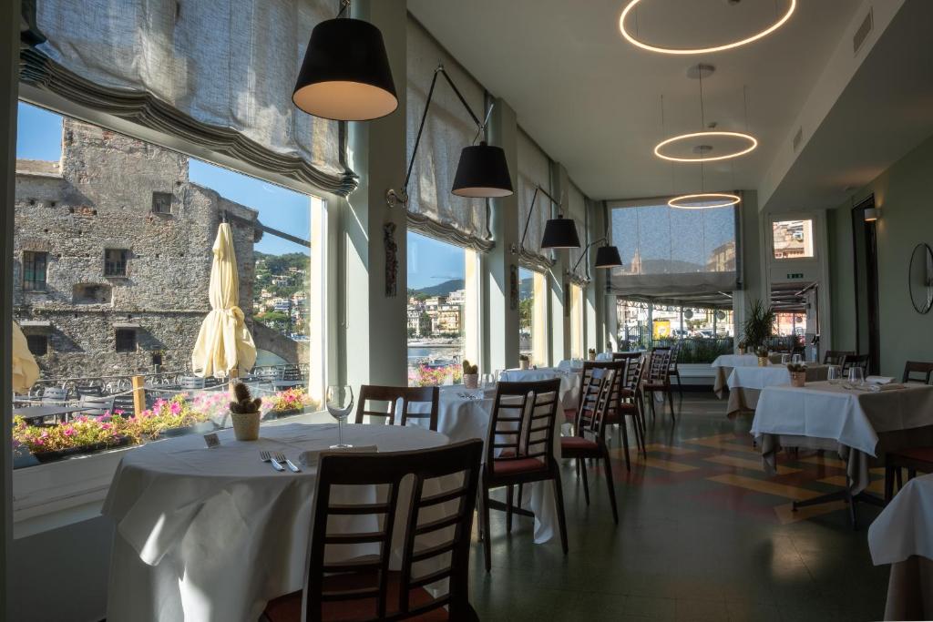 un restaurant avec des tables et des chaises blanches et des fenêtres dans l'établissement Hotel Italia e Lido Rapallo, à Rapallo