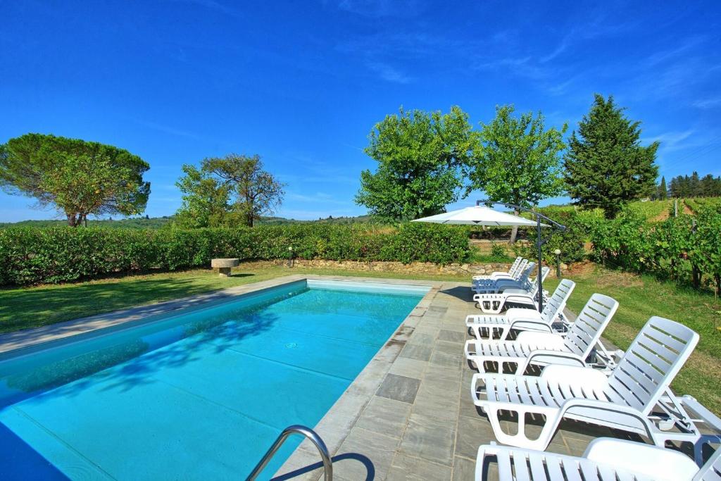 - une rangée de chaises blanches à côté de la piscine dans l'établissement Villa Scerfia by Mmega, à Badia Agnano