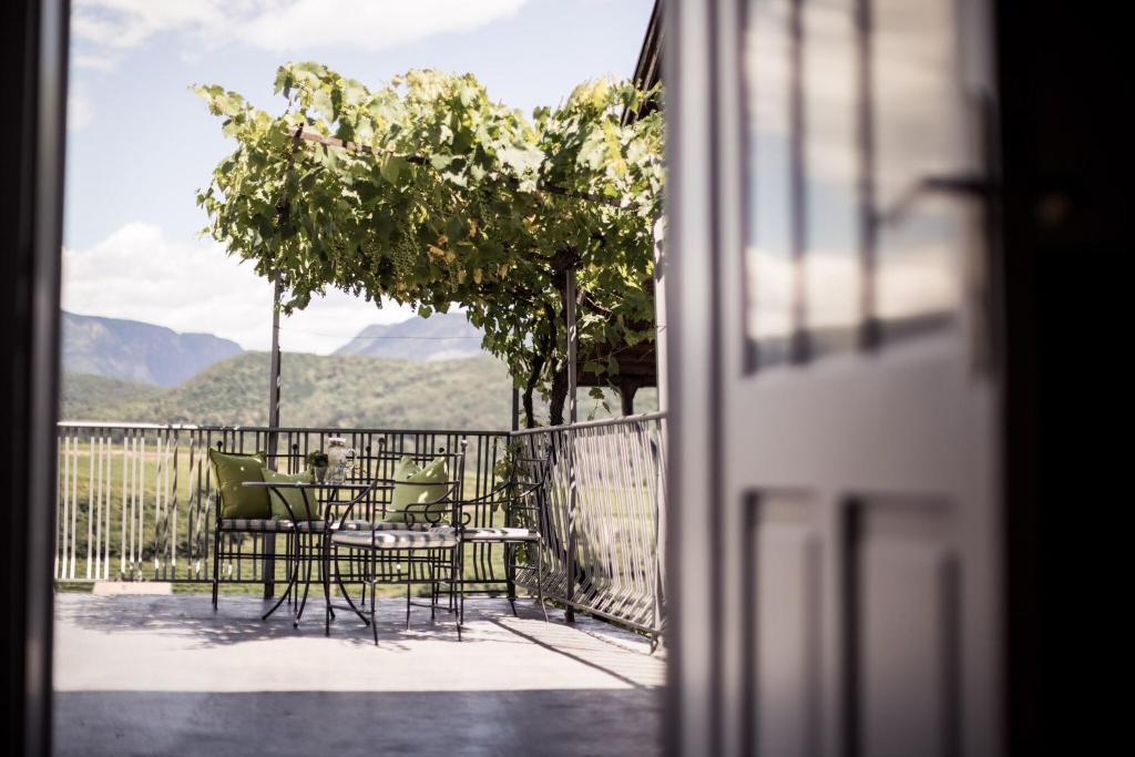une table et des chaises sur un balcon avec vue dans l'établissement Romantik Hotel Jagdhof, à Caldaro