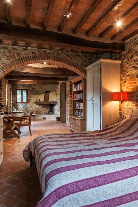 - une chambre avec un grand lit dans un bâtiment en pierre dans l'établissement Podere Gli Oppi Toscana, à Petroio