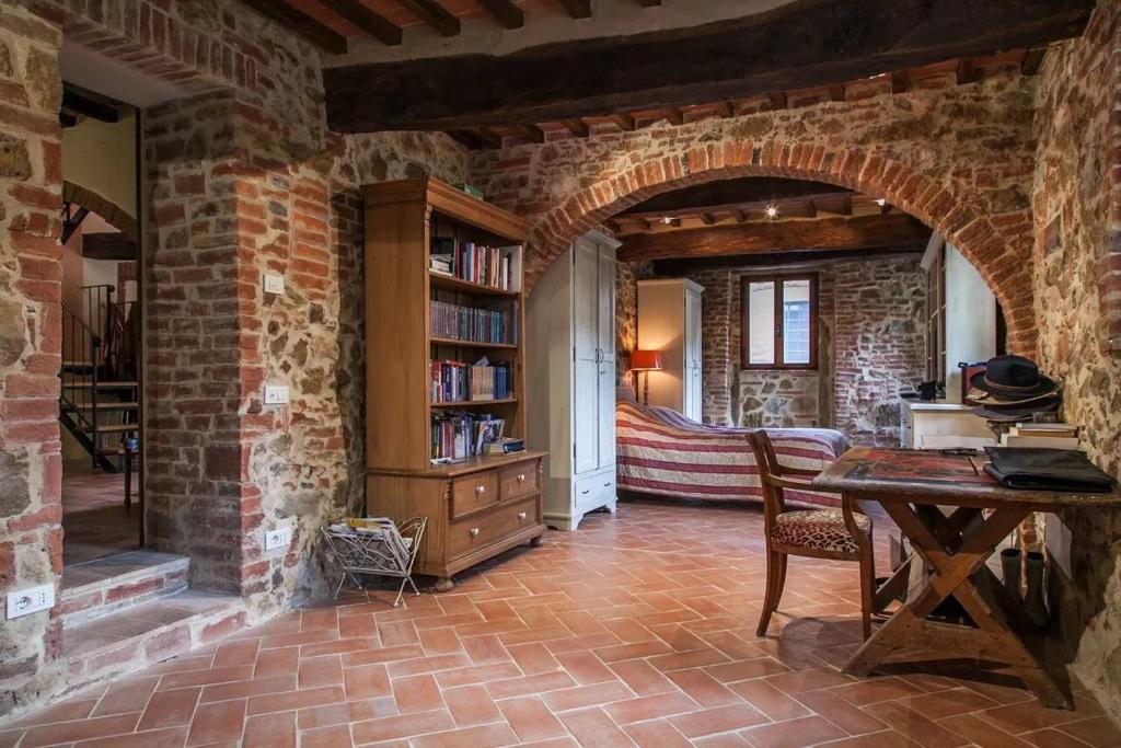 - un salon avec une table et un mur en briques dans l'établissement Podere Gli Oppi Toscana, à Petroio