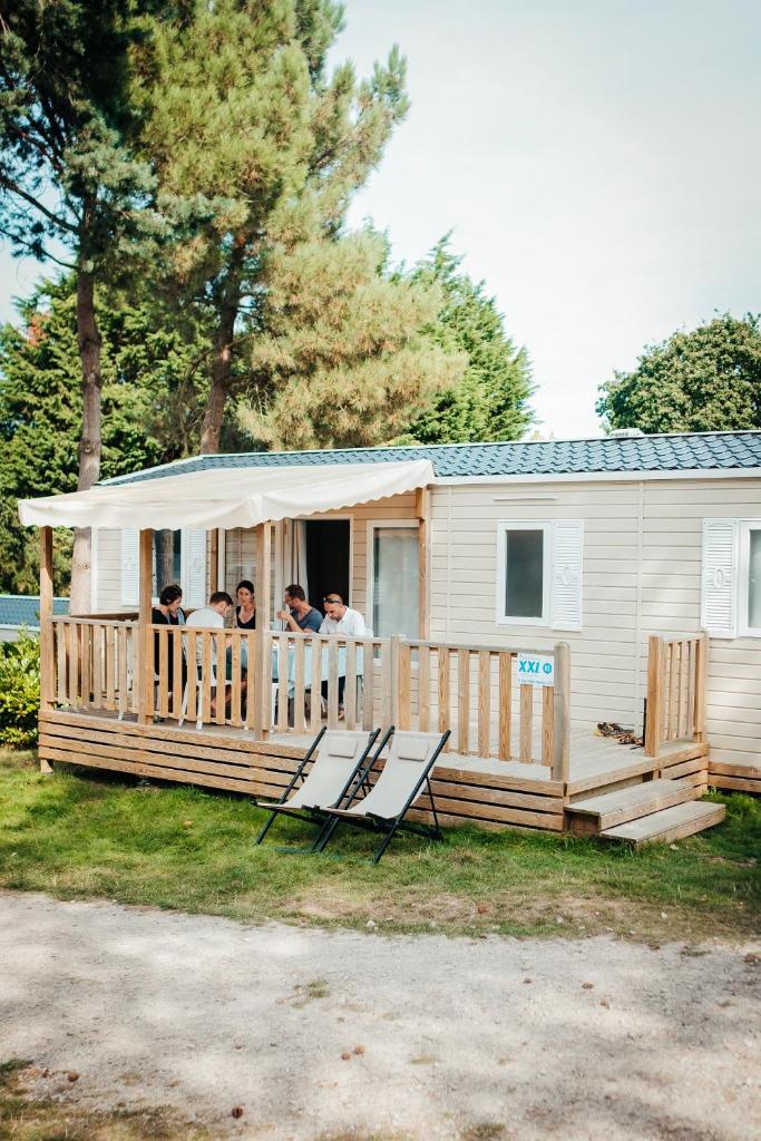 un groupe de personnes assises sur la terrasse couverte d'un mobile home dans l'établissement Mobil Home XXL 4 chambres - Camping Les Lacs d'Armagnac, à Bretagne-dʼArmagnac 5 autres photos