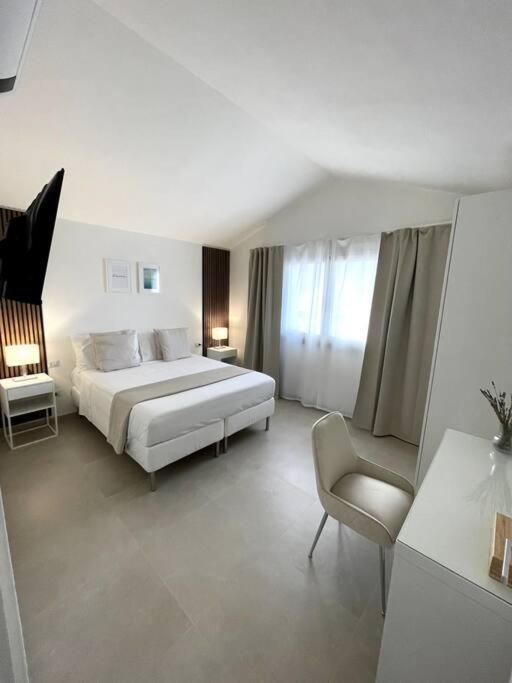 une chambre blanche avec un lit et une chaise dans l'établissement Villa Ami, à Castiadas