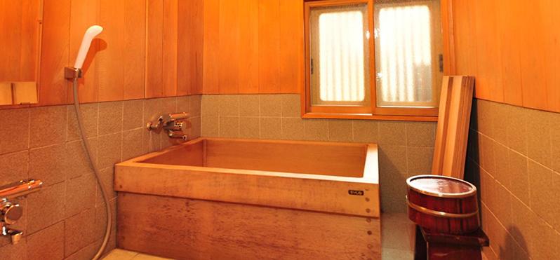 une baignoire en bois dans une salle de bain avec une fenêtre dans l'établissement Ryokan Imai, à Shibata