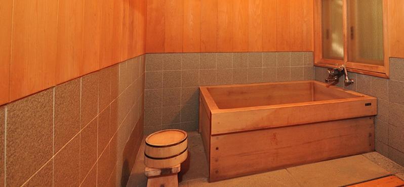 La salle de bains est pourvue d'une baignoire en bois et d'un tabouret. dans l'établissement Ryokan Imai, à Shibata 15 autres photos