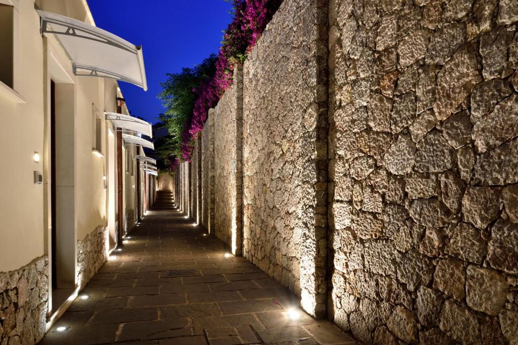 Une allée avec des fleurs sur un mur de pierre la nuit dans l'établissement La Plage Resort, à Taormine 49 autres photos